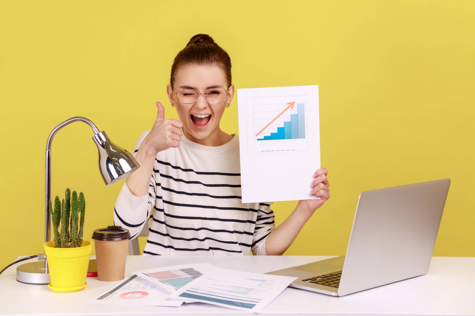 kvinne smiler og har tommel opp, med en graf som viser vekst i hånden